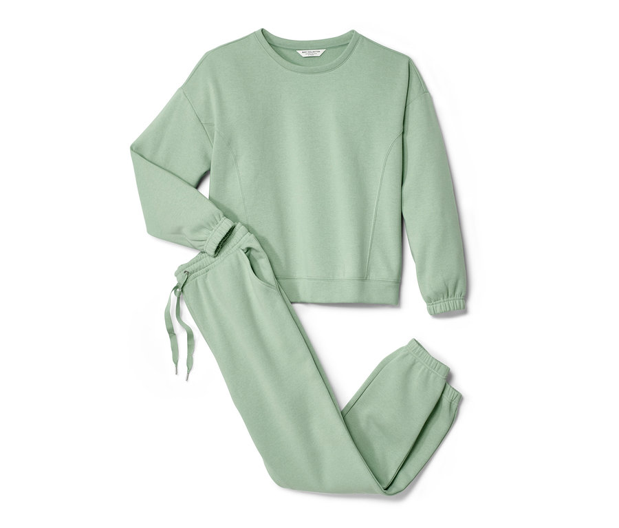 Ein grüner Hausanzug mit Sweatshirt und Jogginghose liegt auf einem weißen Hintergrund.