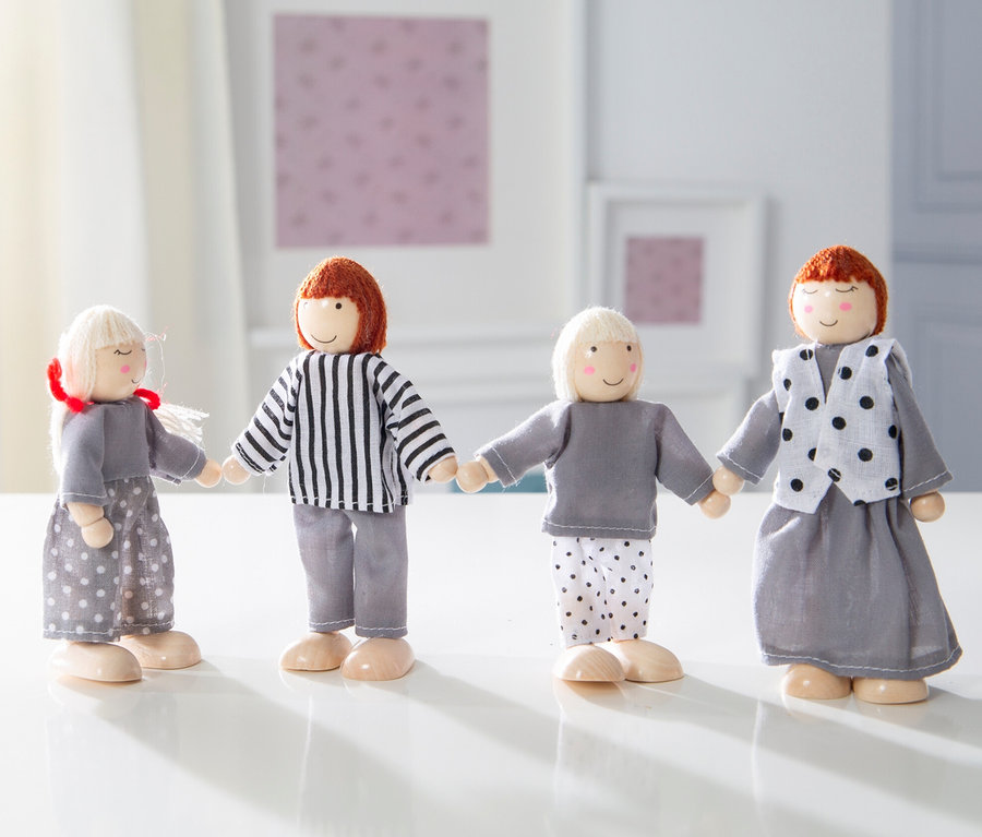 Vier Holzfiguren aus dem roba Puppenhaus inkl. Zubehör stehen nebeneinander und halten sich an den Händen auf einem weißen Tisch.