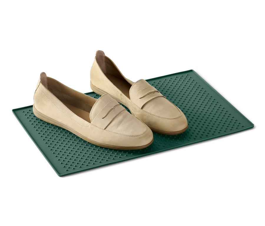 Zwei beige Slipper auf einem grünen Futternapf-Untersetzer.
