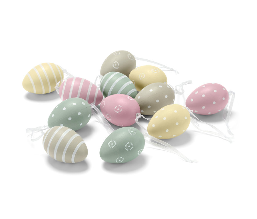 Zwölf Ostereier mit verschiedenen Mustern liegen auf einer weißen Oberfläche.