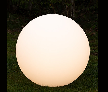 Eine leuchtende 8 seasons design Solar-Leuchtkugel, 60 cm, liegt auf einer Wiese.