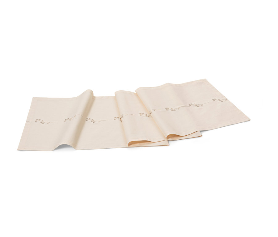 Ein bestickter, beiger Tischläufer mit Zweig-Motiv.