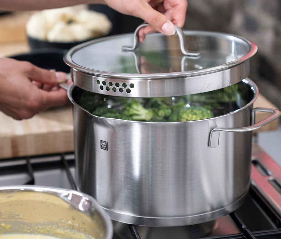 Person hebt Deckel von ZWILLING Trueflow Kochtopf mit Brokkoli auf Herd.