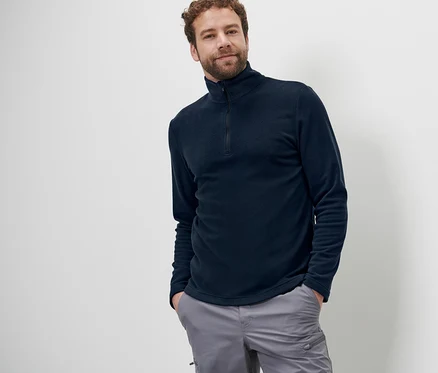 Mann posiert in Mircofleece-Shirt und grauer Hose.