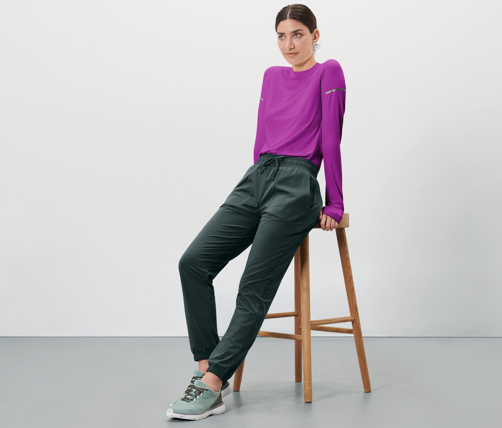 Eine Frau sitzt auf einem Hocker und trägt eine Thermo-Funktionshose.