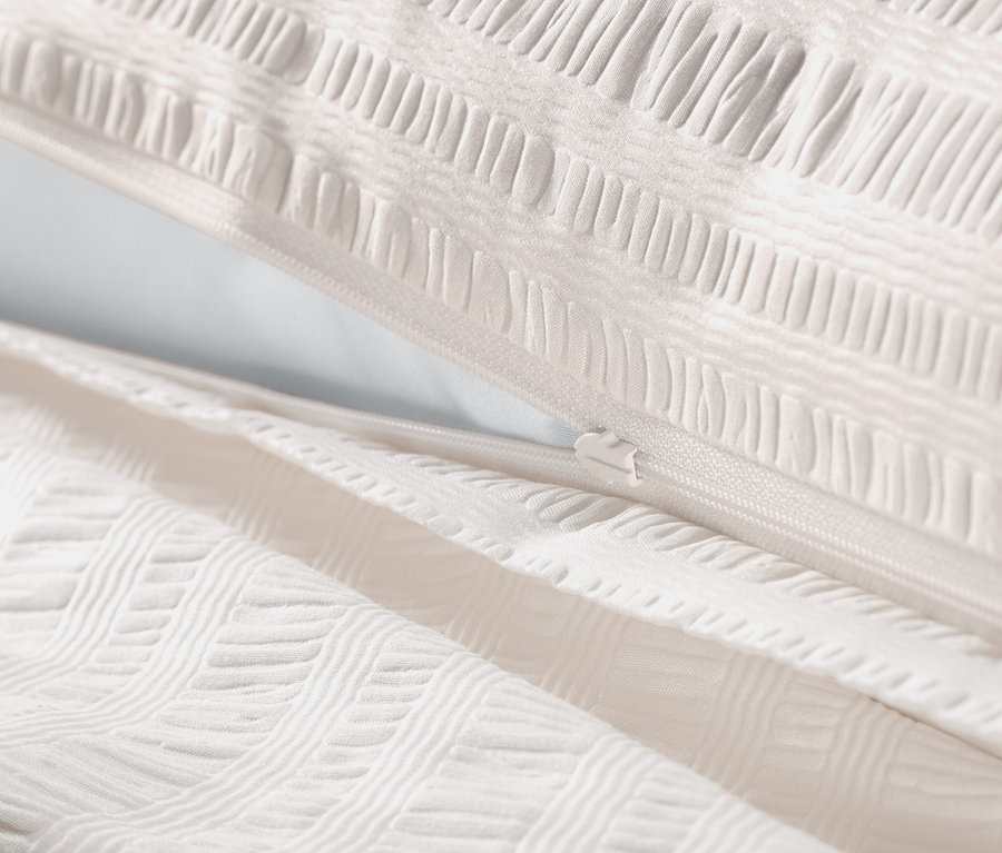 Detailansicht von offweißer Seersucker-Bettwäsche in Normalgröße und Übergröße mit Reißverschluss.