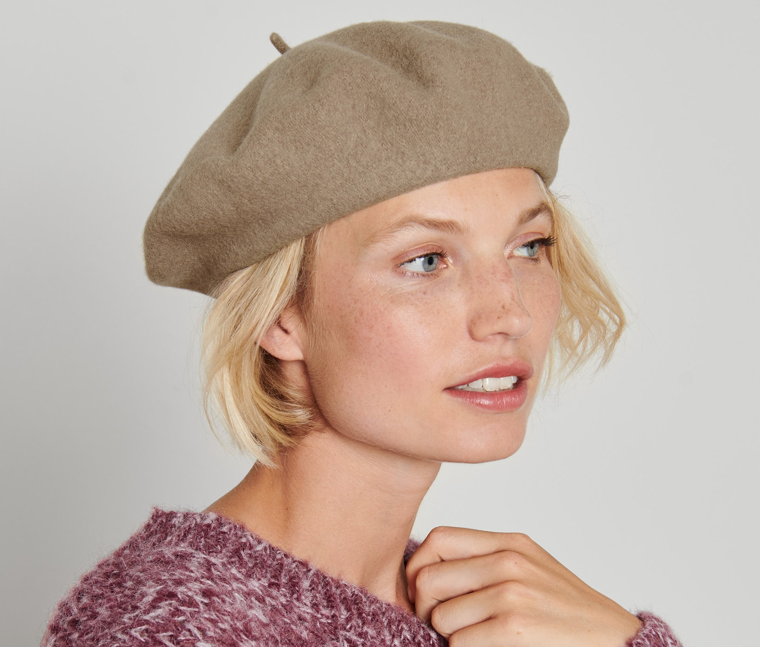 Frau mit blonden Haaren trägt eine Baskenmütze.