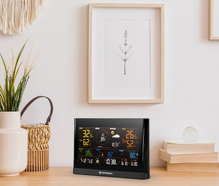 Schwarze BRESSER WLAN Comfort-Wetterstation mit 7-in-1-Profi-Sensor auf einem Holztisch.