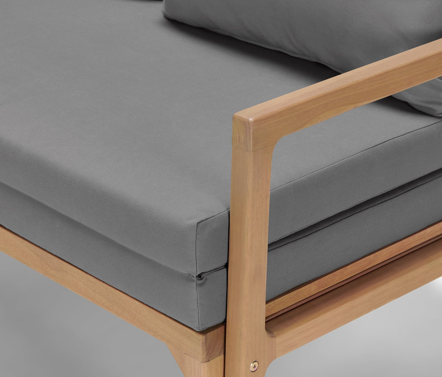 Detailaufnahme eines Loungesofas mit ausziehbarem Fußteil und grauen Kissen.