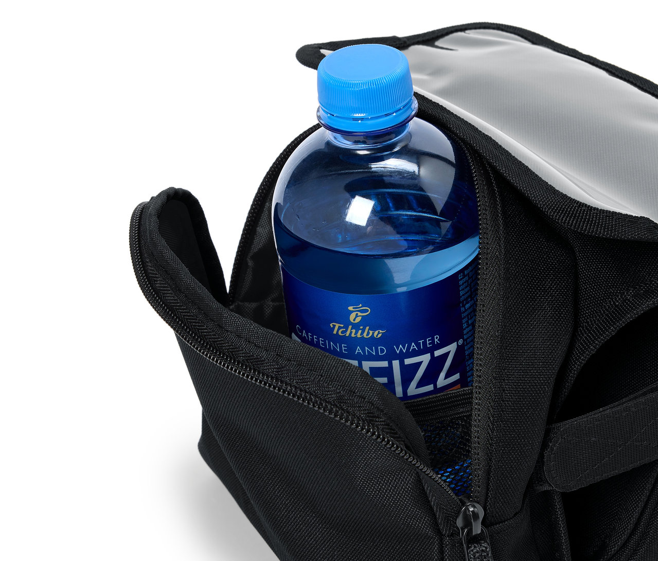 Eine blaue Flasche Tchibo Caffeine and Water Fizz steckt in einer offenen schwarzen Tasche.