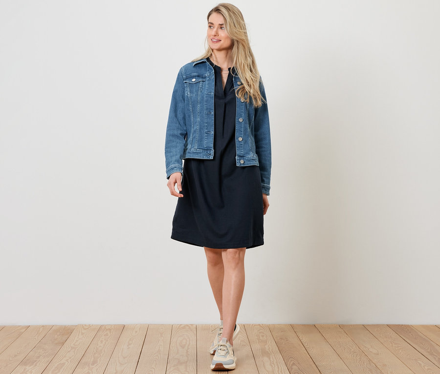Frau trägt eine Jeansjacke und ein Leinenkleid.