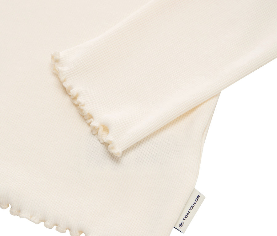 Detail eines cremefarbenen, gerippten Langarmshirts mit Rüschenkante und Tom Tailor Etikett.