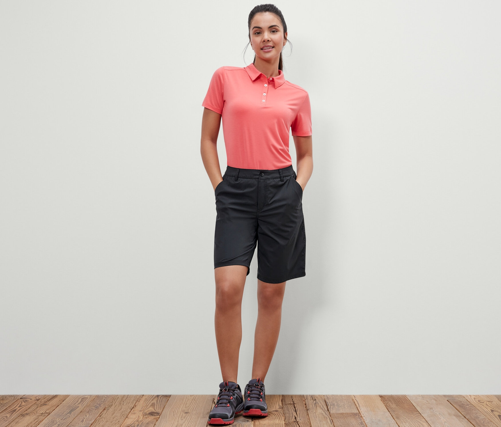 Frau steht mit Händen in den Taschen der schwarzen Softshell-Funktionsshorts.