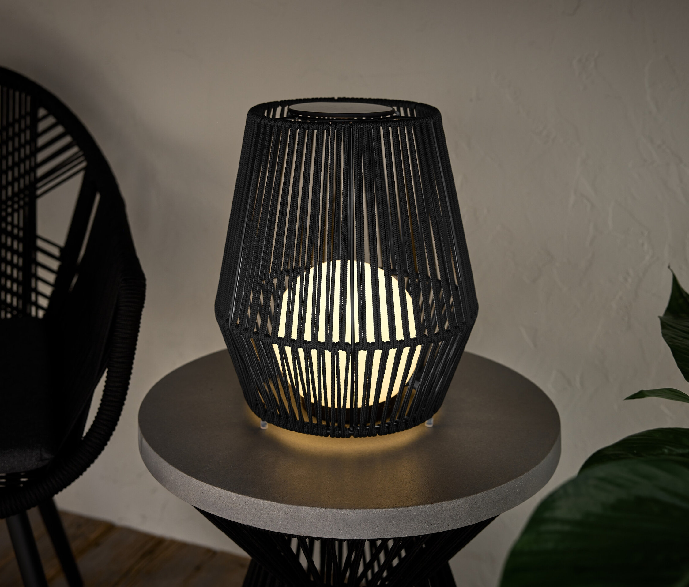 Eine kleine Solar-Laterne mit Textilband steht auf einem Tisch.