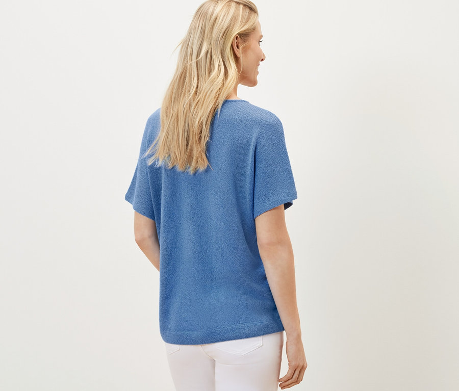 Frau von hinten in blauem, strukturiertem Shirt.