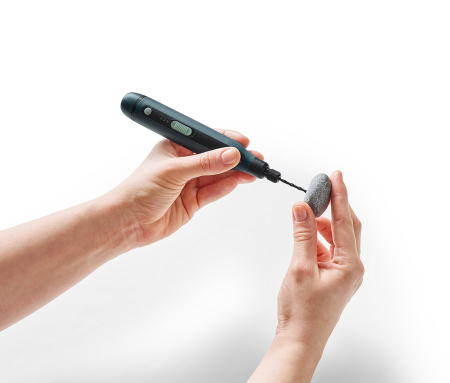 Hände halten einen Stein, der mit einem 3,7-V-Akku-Multifunktionswerkzeug bearbeitet wird.