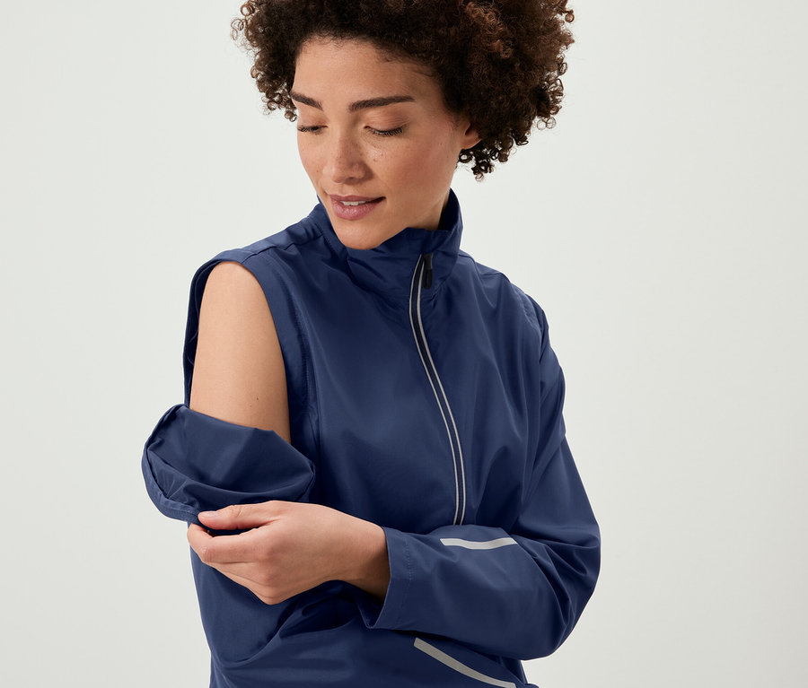 Frau entfernt die Ärmel einer 2-in-1-Fahrradjacke.