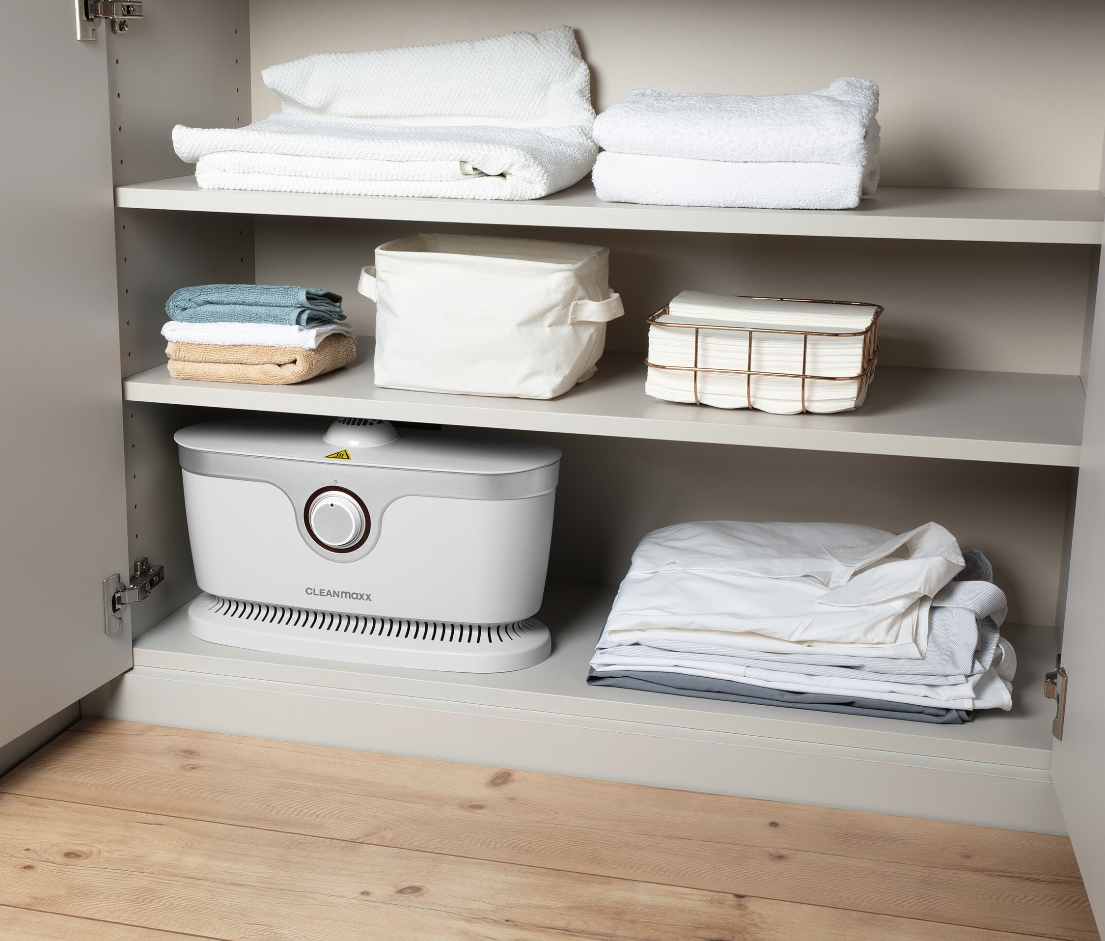 Offener Schrank mit weißem Hemden-und-Blusenbügler auf einem Regal und Handtüchern und Aufbewahrungskörben auf anderen Regalen.