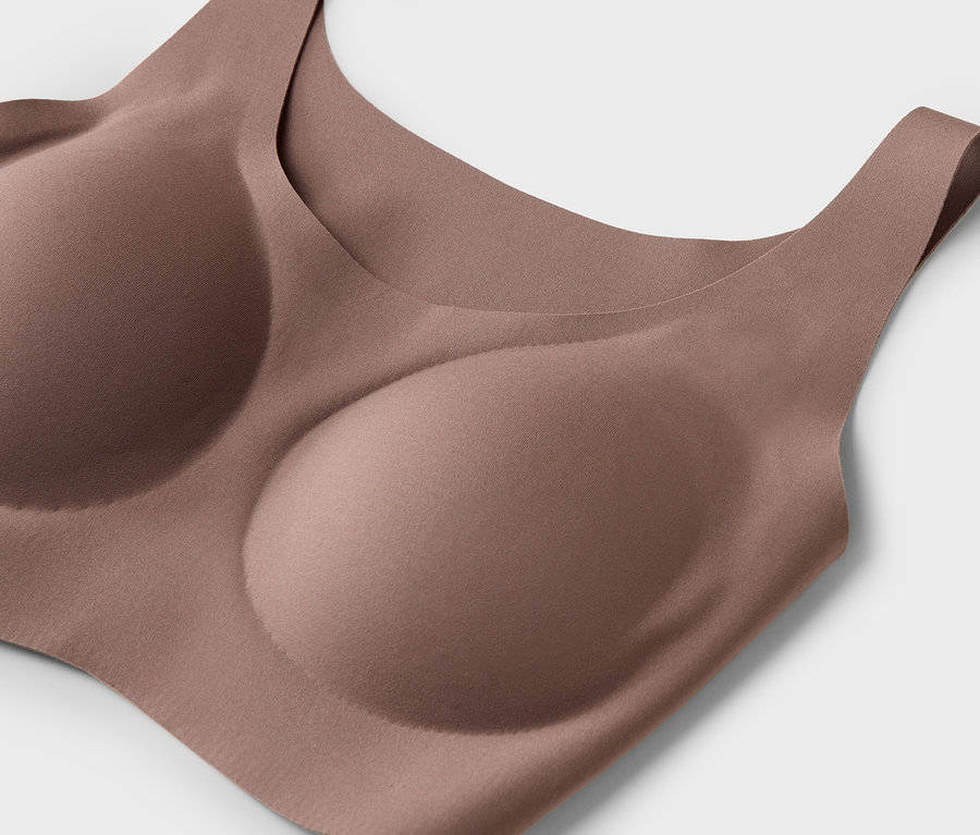 Nahaufnahme eines hautfarbenen BHs mit geformten Cups vor einem weißen Hintergrund.