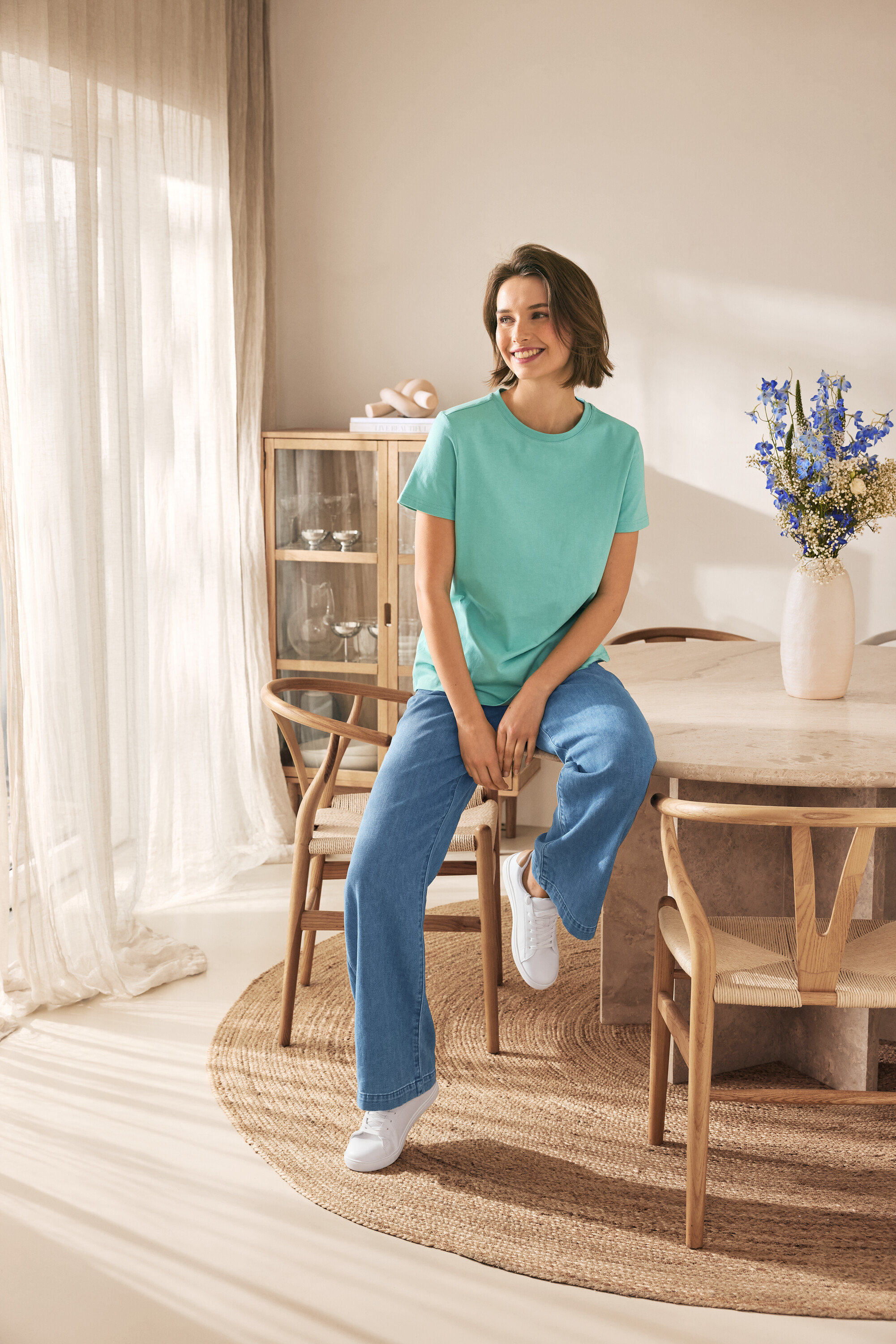 Frau sitzt auf einem Stuhl und trägt Leder-Sneaker.