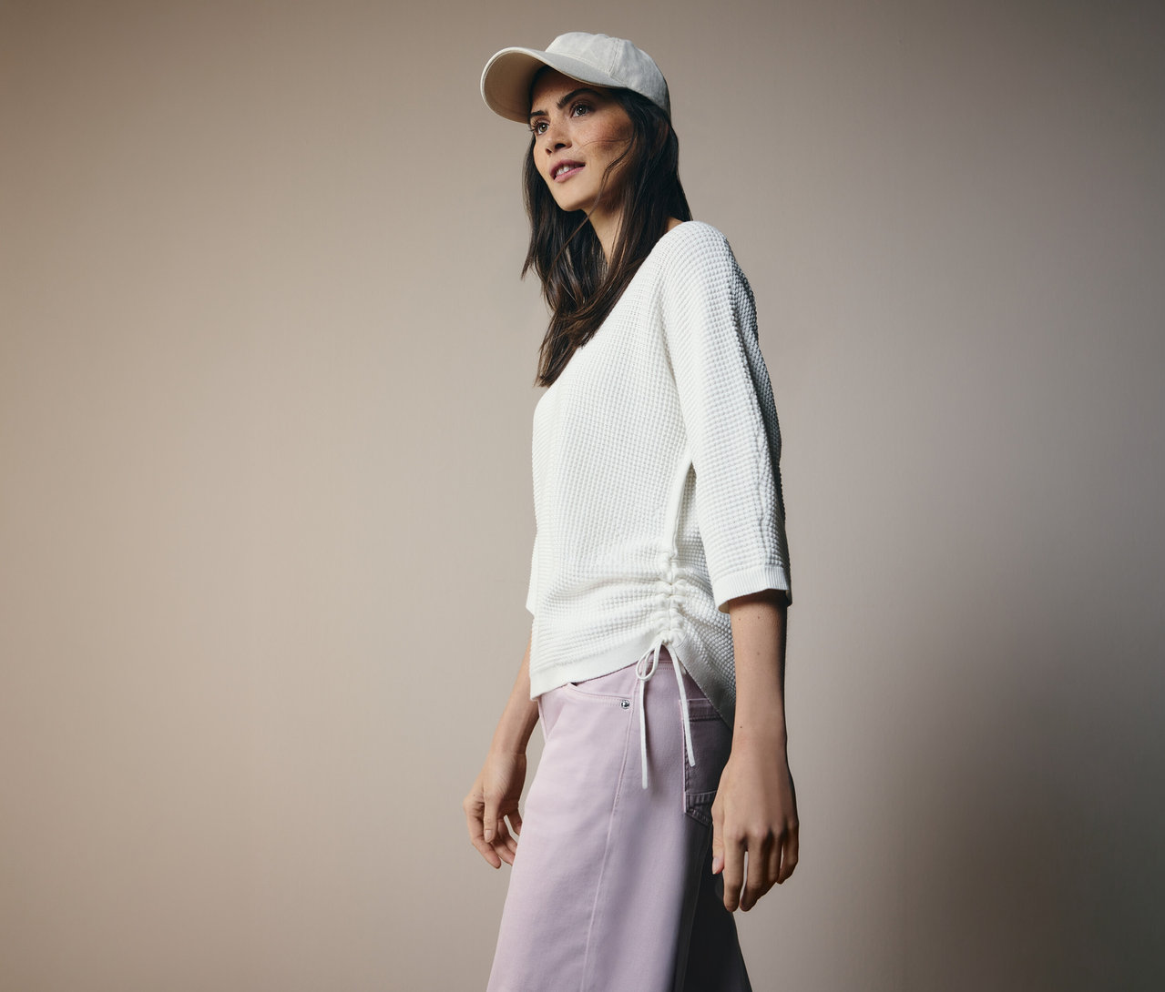 Frau mit Basecap und CECIL Feinstrickpullover mit Tunnelzug an der Seite und rosa Hose.