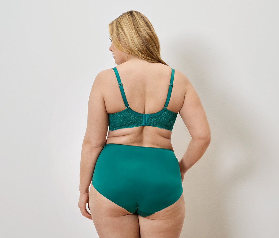 Rückansicht einer Frau mit blonden Haaren, die einen grünen BH mit Spitze und einen hoch taillierten Slip trägt.