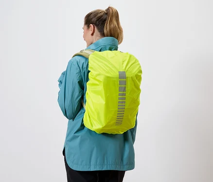 Rückansicht einer Frau mit blauem Regenmantel und gelber Rucksackhülle mit reflektierenden Streifen vor einem weißen Hintergrund.