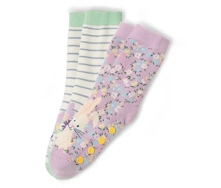Drei Sockenpaare liegen auf einem weißen Hintergrund. Ein Paar ist lila mit einem Blumenmuster und einem Hasenaufdruck. Ein Paar ist weiß mit blauen Streifen und einem grünen Bund.