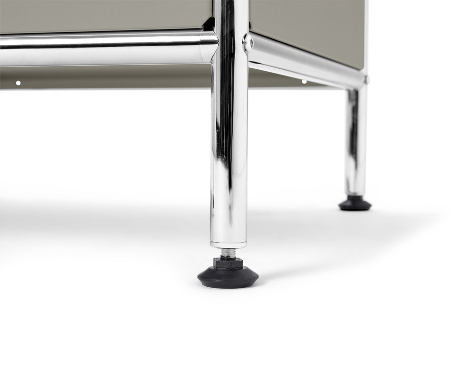 Nahaufnahme der verchromten Beine eines grauen Möbelstücks mit schwarzem Fuß.