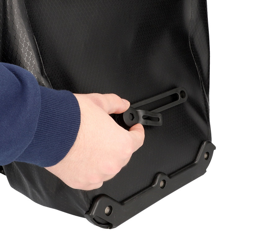 Hand befestigt eine schwarze Halterung an einer schwarzen wasserdichten Tasche.