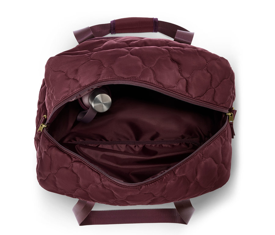 Offene, gesteppte, weinrote Tasche mit silberner Wasserflasche im Inneren.