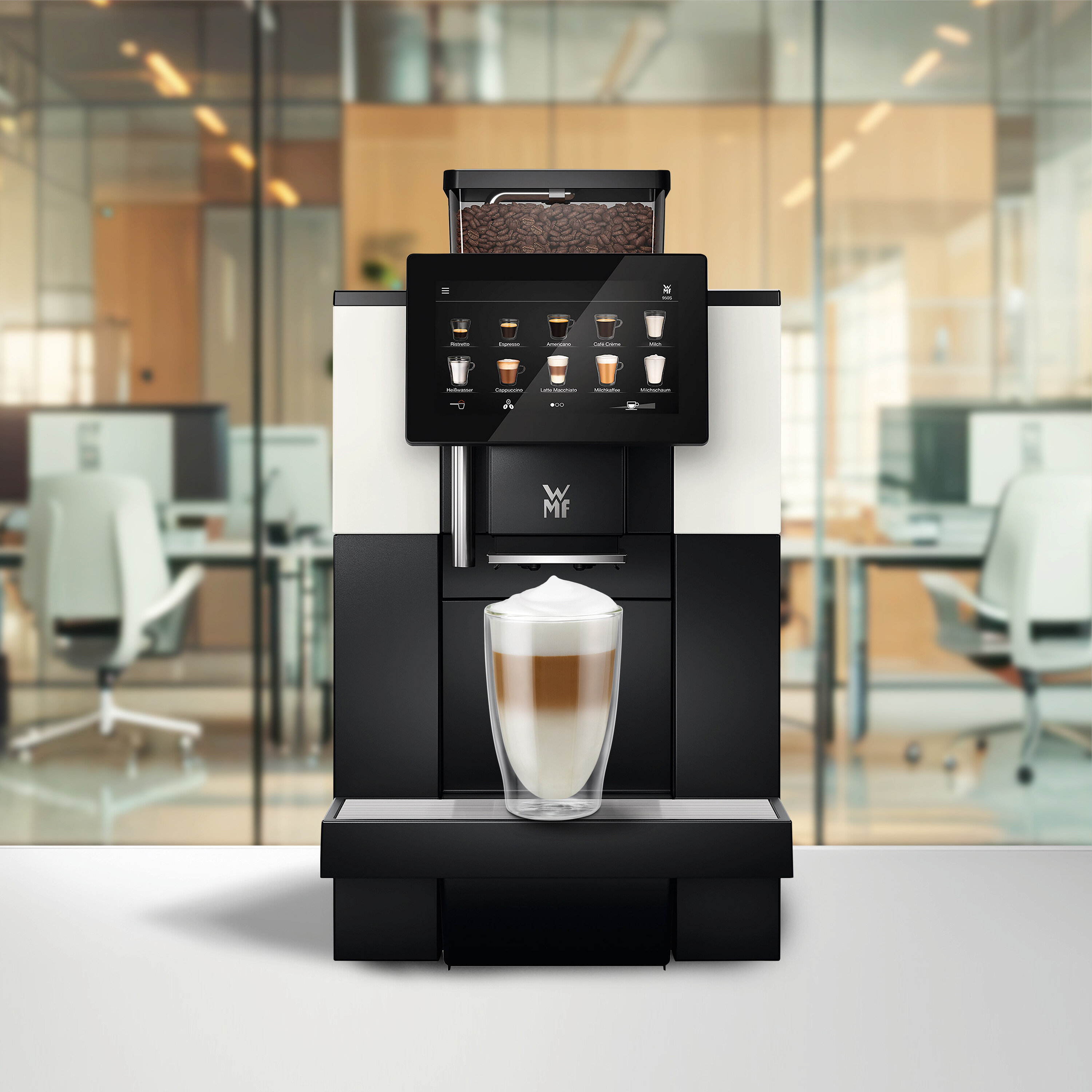 Ein Kaffeevollautomat mit Touchscreen, der Getränkeoptionen anzeigt, und einem Bohnenbehälter voller Kaffeebohnen. Ein Glas geschichteter Latte Macchiato steht auf der Abtropfschale, im Hintergrund ein verschwommenes Büro.