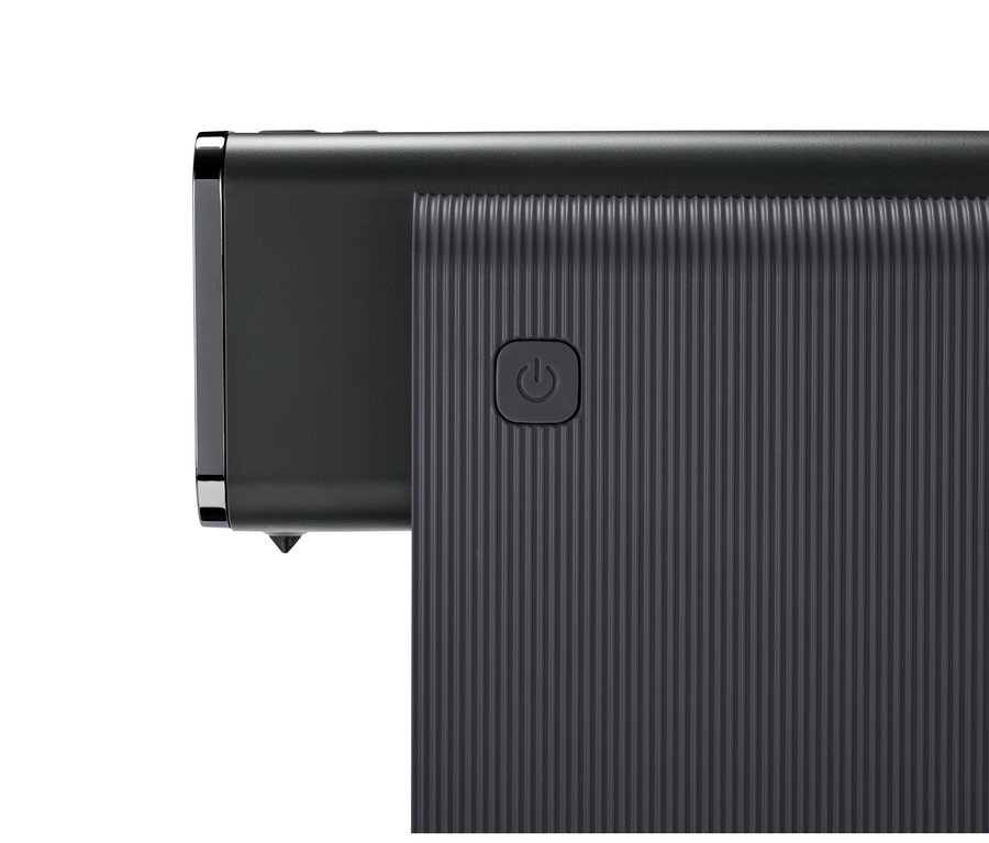 Nahaufnahme eines dunkelgrauen Elektronikgeräts mit gerippter Oberfläche und einem Ein-/Ausschalter. Die linke Seite hat eine glatte Oberfläche mit Metallzierleiste.