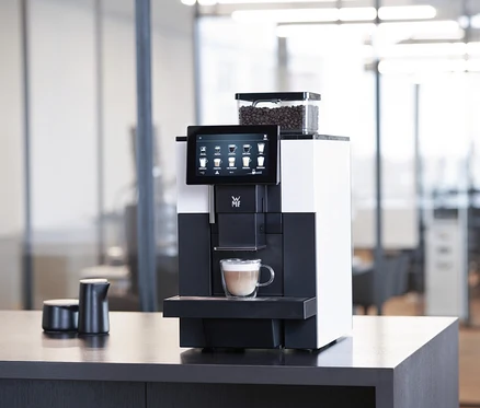 WMF 950 S Profi-Kaffeevollautomat mit Tasse Cappuccino auf einem Tisch.