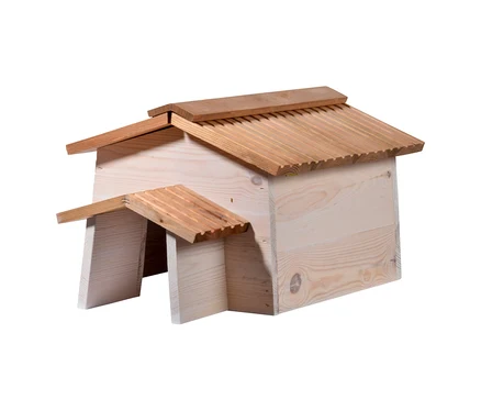 Ein helles Holzhaus mit einem dunklen, geriffelten Giebeldach und einem kleineren, überdachten Eingang auf der linken Seite, ebenfalls mit geriffelten Dach.