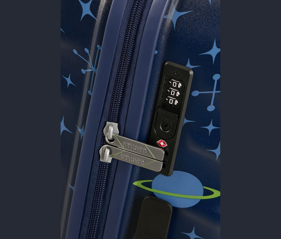 Nahaufnahme eines dunkelblauen Koffers mit hellblauen Sternen und Planetenmuster. Ein dunkelblauer Reißverschluss ist mit zwei silbernen Zippern mit „AMERICAN TOURISTER“ und grünen Linien versehen, die in ein schwarzes Zahlenschloss mit der Einstellung „000“ und einem roten TSA-Logo eingesteckt sind.
