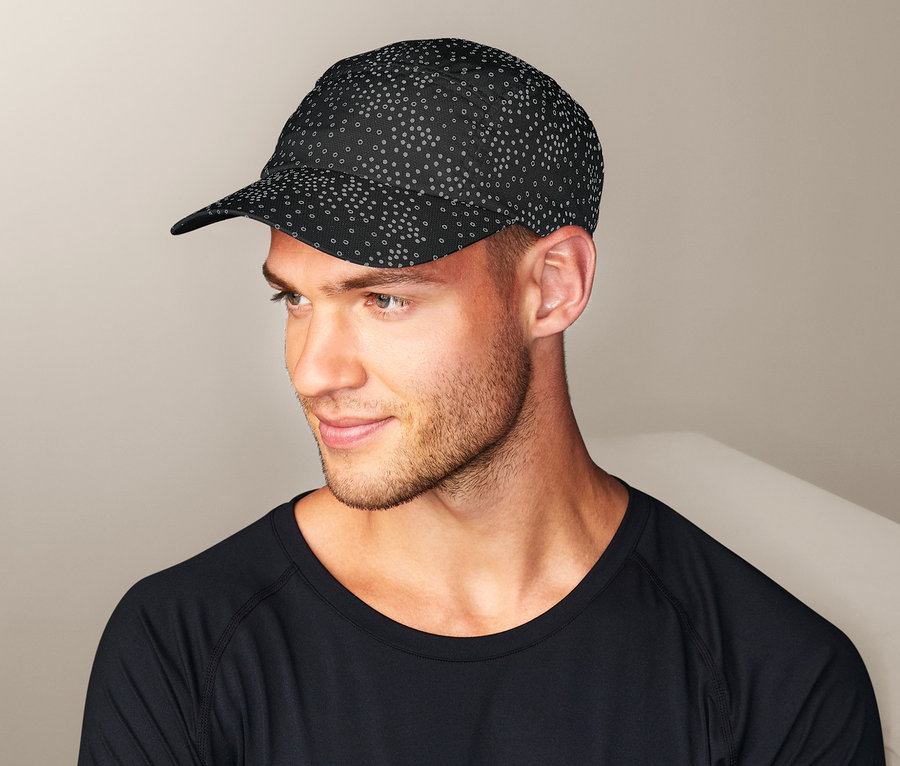 Mann mit verschränkten Armen trägt eine schwarze Reflektor-Sportcap und ein schwarzes Langarmshirt.