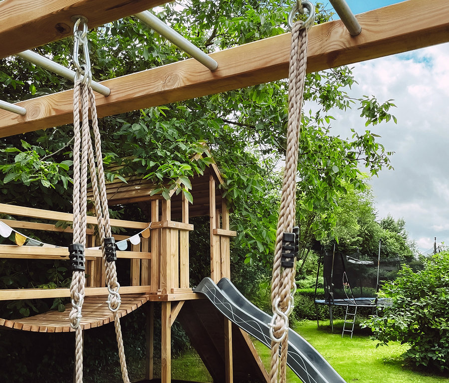 Spielplatz mit Holzrahmen, Rutsche und small foot Skateboard-Schaukel.