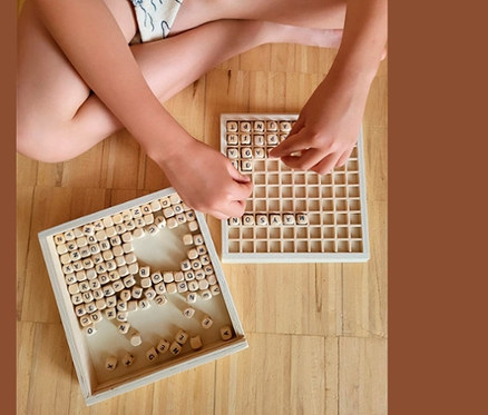 Kind sitzt am Boden und spielt mit small foot Wörter legen »Educate«.
