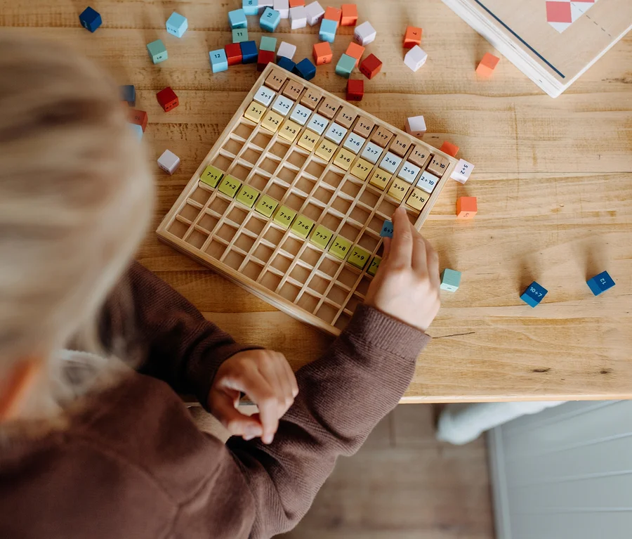 Kind spielt mit small foot Rechen-Set »Educate« auf einem Holztisch.