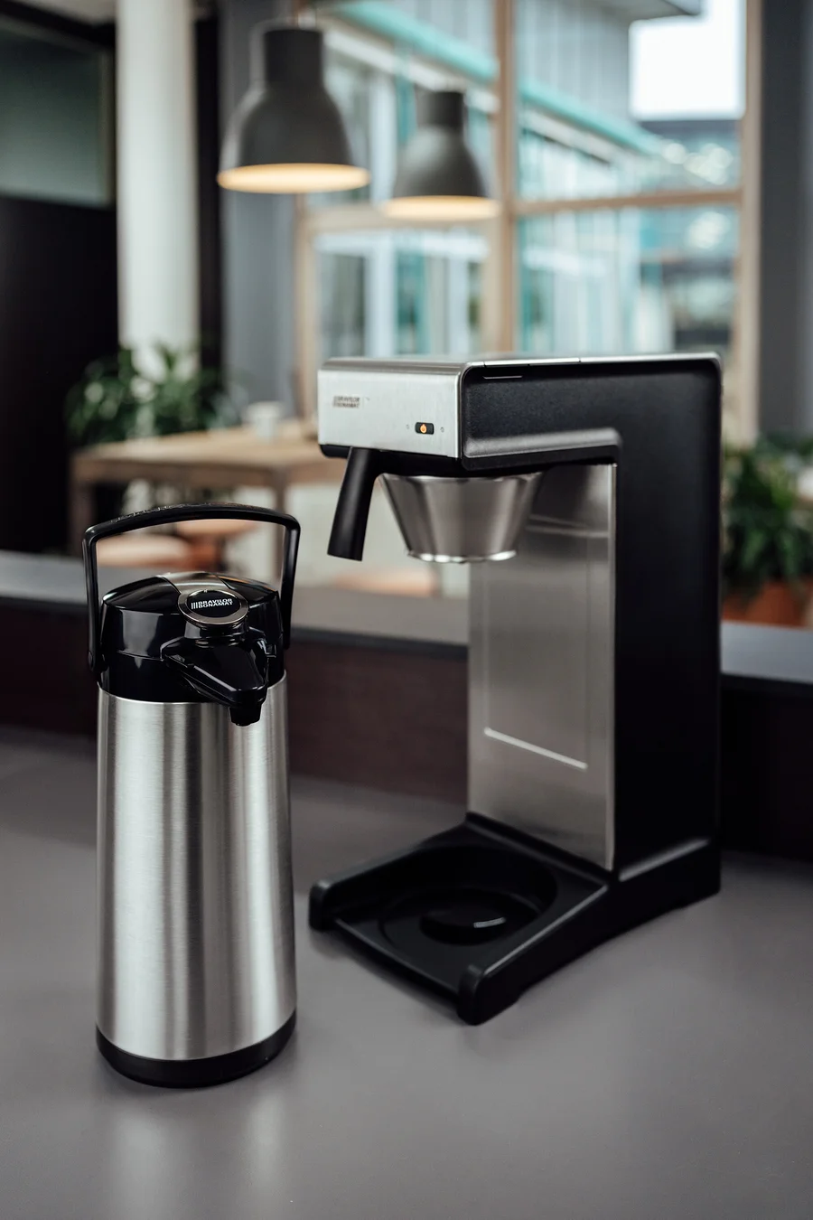 Eine silberne Bonamat Pumpthermoskanne 2,2 l neben einer professionellen Bravilor-Bonamat TH Filterkaffeemaschine ohne Kanne.