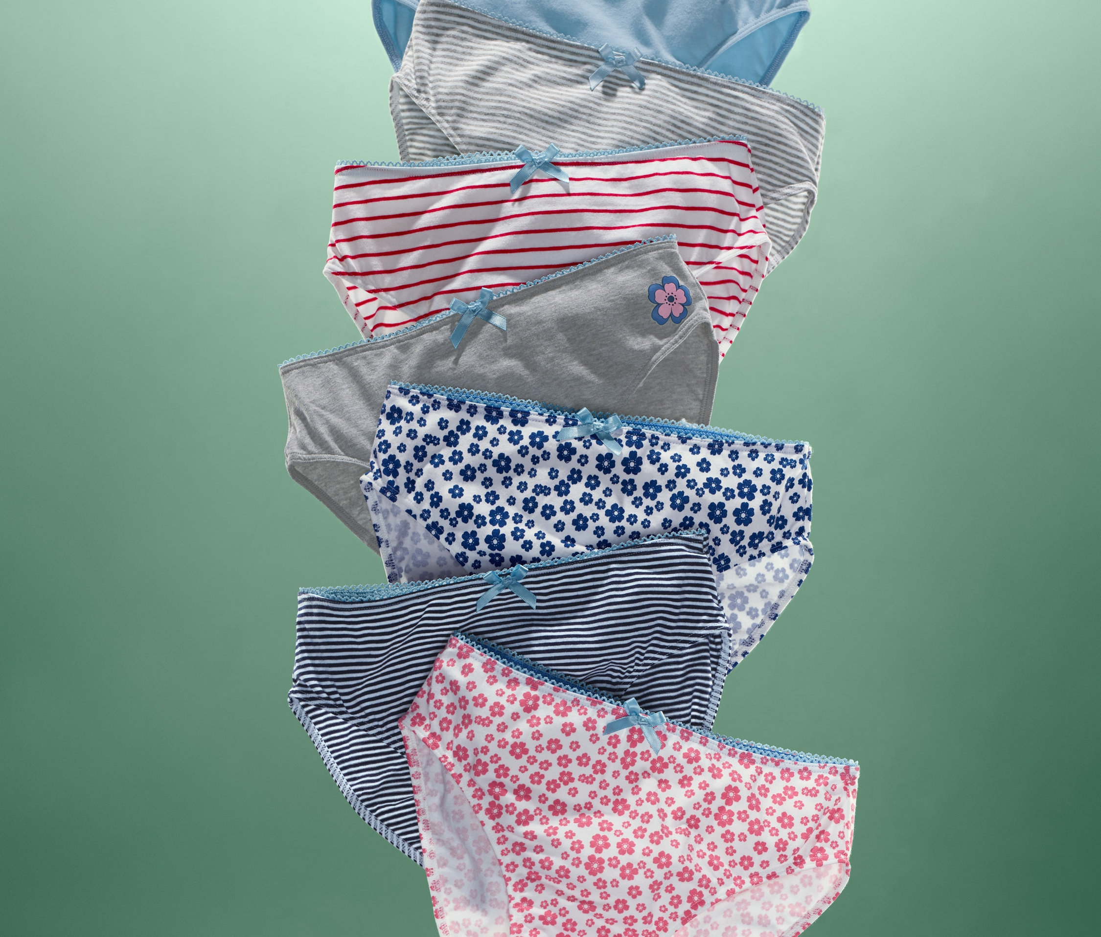 Auf grünem Hintergrund sind 7 Slips in verschiedenen Farben und Mustern zu sehen.