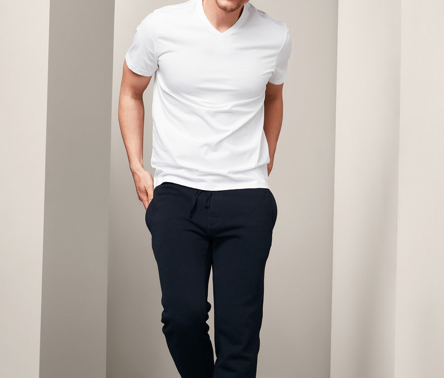 Mann trägt ein weißes T-Shirt und eine Sweathose.