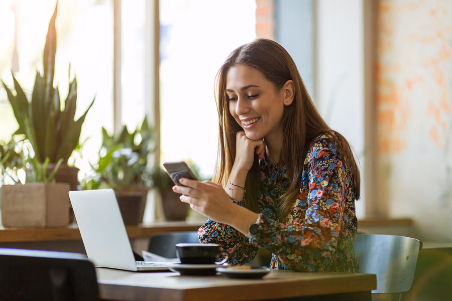 Une femme souriante regarde son smartphone