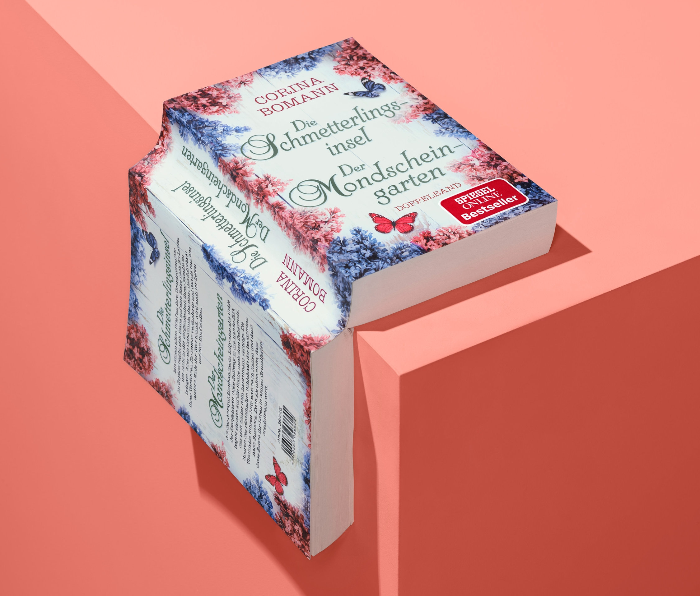 Zwei Romane 'Die Schmetterlingsinsel' und 'Der Mondscheingarten' liegen auf korallfarbener Oberfläche.