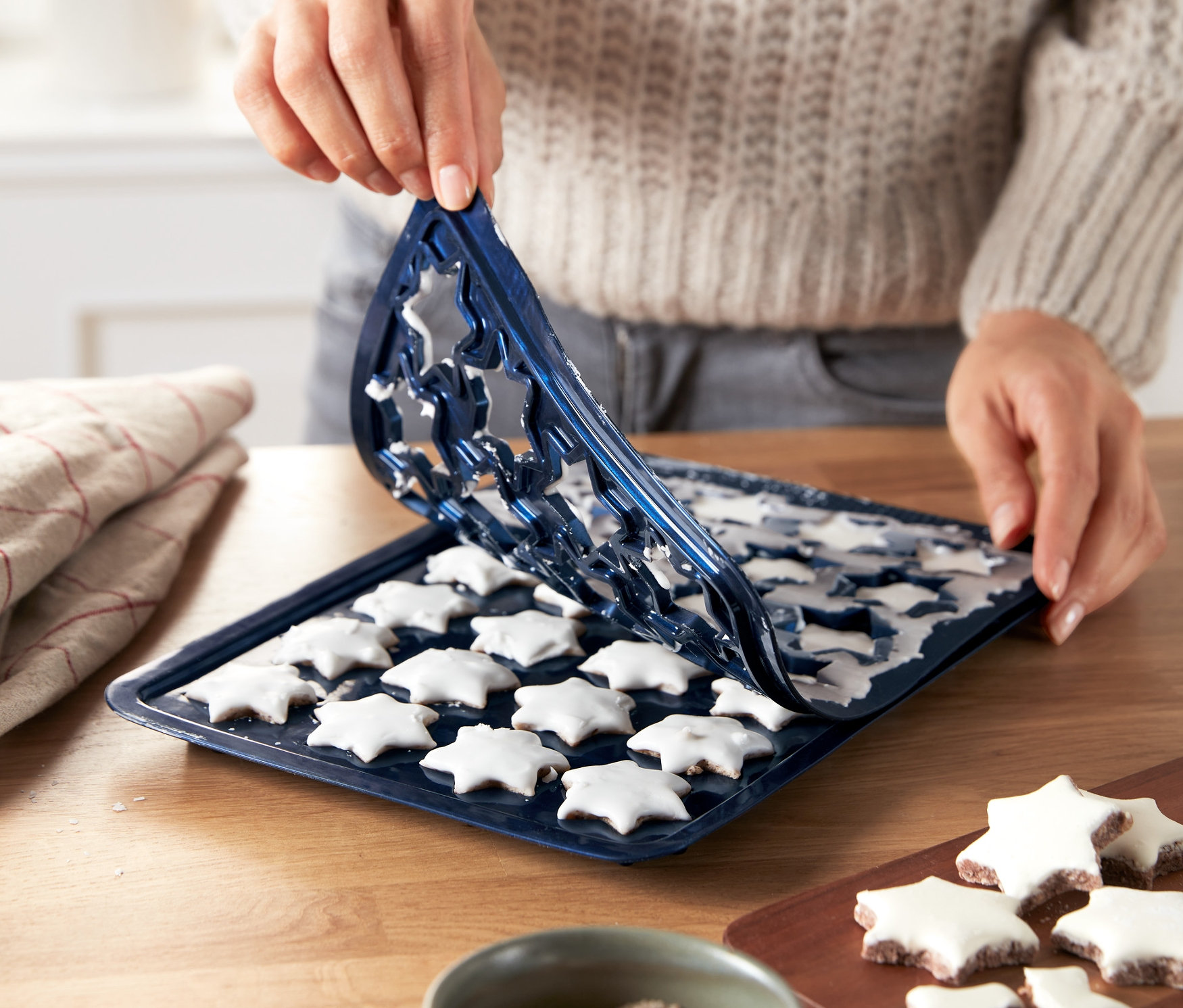 Frau löst Zimtsterne von der Zimtstern-Backmatte.