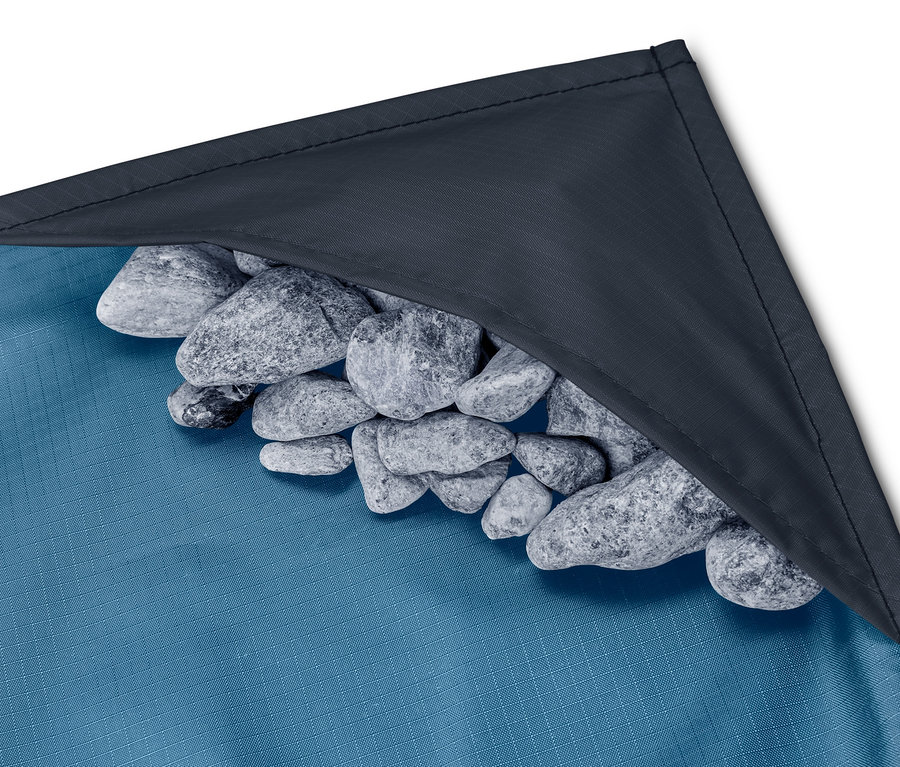 Detailaufnahme einer blauen Mini-Picknickdecke mit einem Haufen Steine in der Ecke.