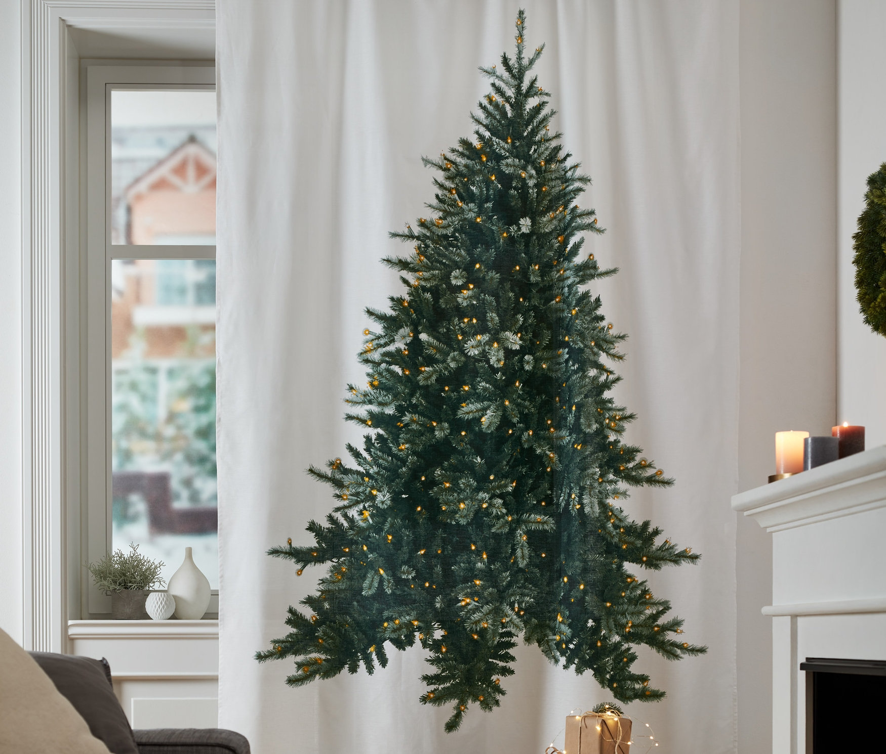 Ein weißer Motiv-Vorhang mit einem Weihnachtsbaum hängt am Fenster.
