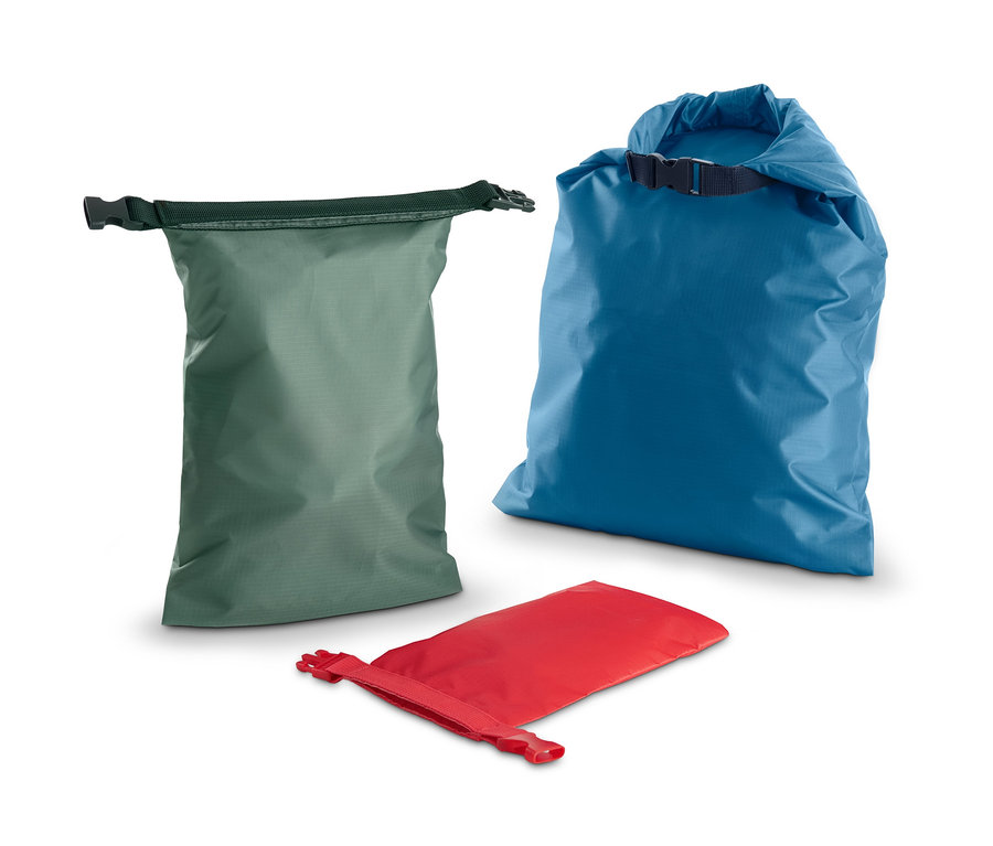 Drei wasserfeste Packsäcke sind dargestellt: ein grüner, ein blauer und ein roter.