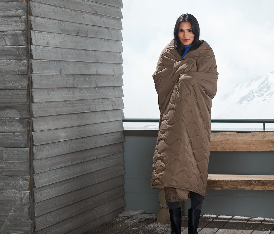 Frau eingehüllt in eine Outdoor-Thermodecke.